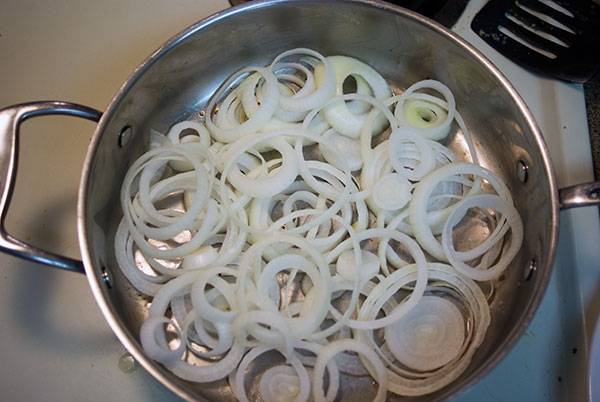 Layer onions for Baked Chicken Leg Quarters with Caramelized Onions.