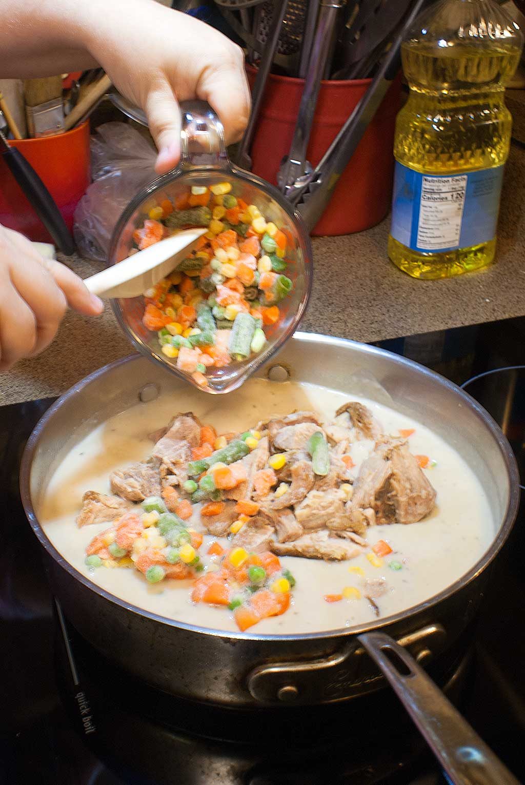 Adding leftover turkey and frozen mixed vegetables to soup mixture