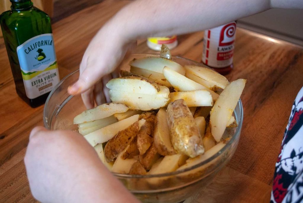 Mixing potato wedges and spices together