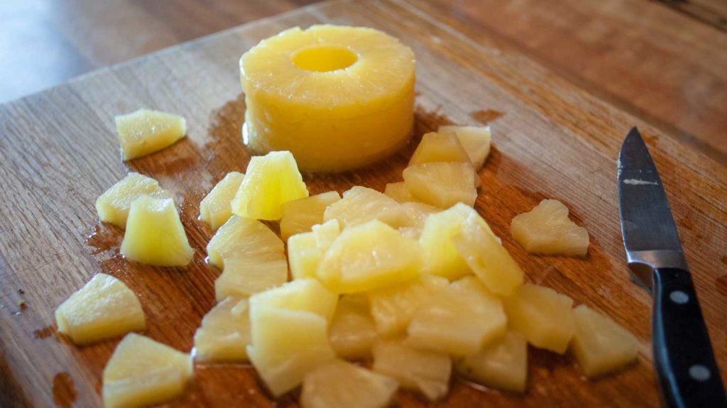 CAnned pineapples being cut for pork and pineapple rice bowls
