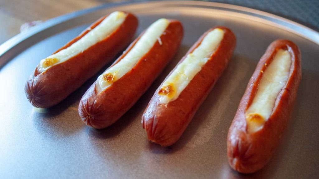 Cooked sausages stuffed with melted and browned string cheese