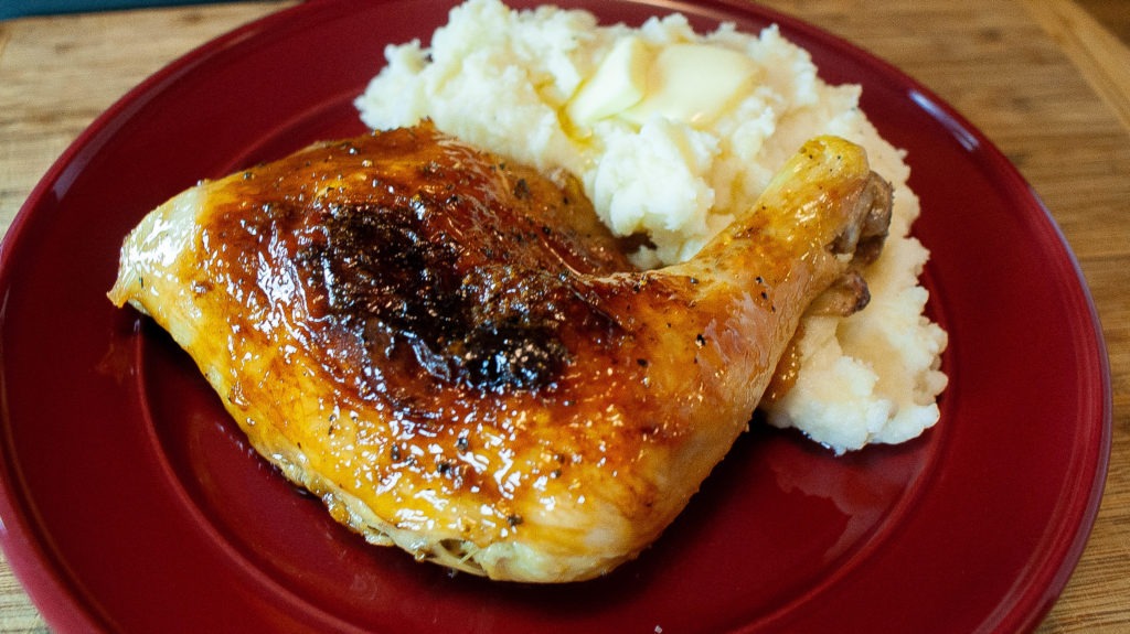 Plum glazed chicken leg quarters plated with lemon garlic mashed potatoes