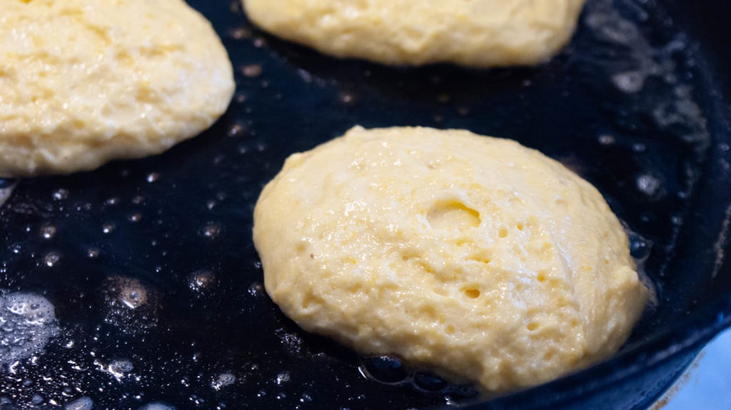 hoecakes cooking in a cast iron skillet