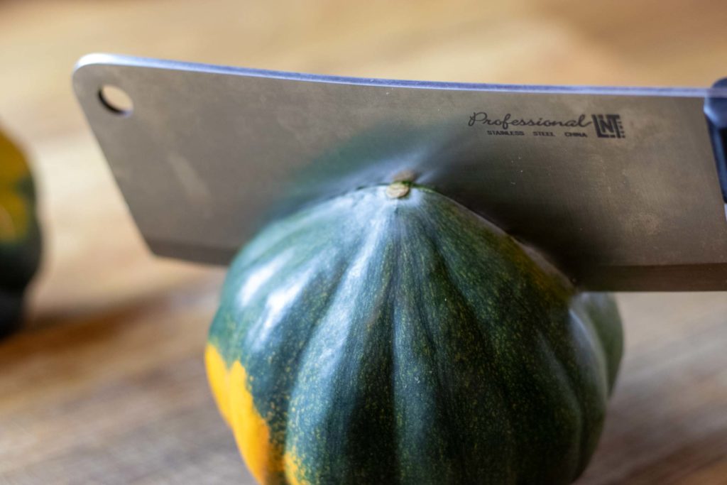 Cleaver cutting acorn squash in half