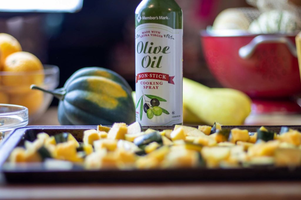 Olive oil spray with cubed squash in foreground
