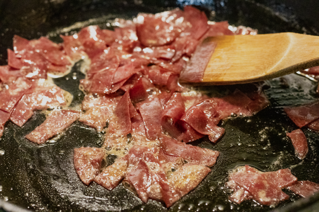 Chipped beef cooking in a skillet with butter